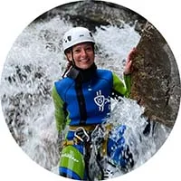 A woman canyoneer descends down a safe natural waterfall slide in Soča canyon.