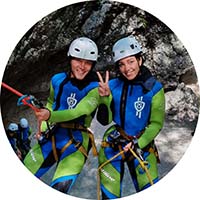 A smiling couple is rappelling down the waterfalls in Soča river valley. They are filled with adrenaline.